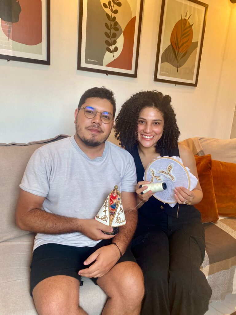 Emanoel e Emmily dão continuidade à missão deixada por dona Conceição, transformando cada ponto do manto em um gesto de amor e devoção