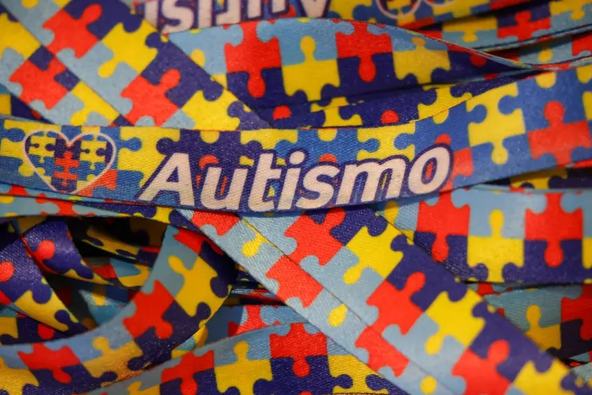 Cordão estampado com padrão de quebra-cabeça colorido e a palavra "Autismo".