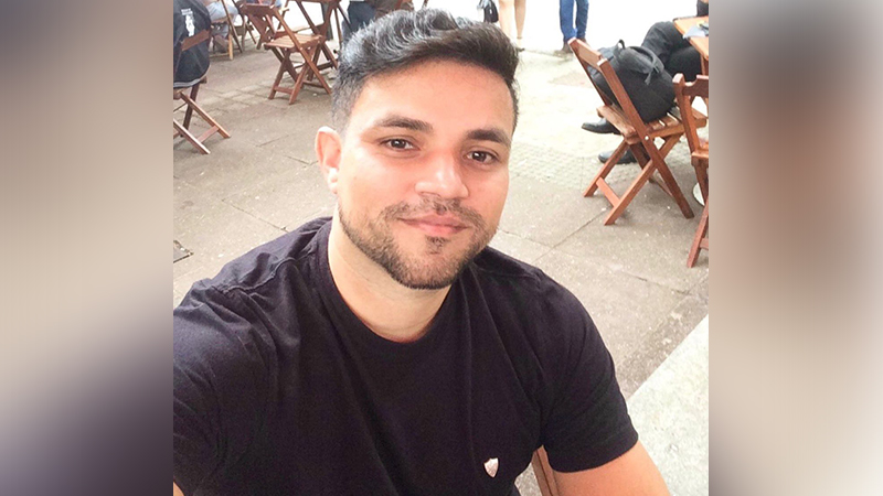 Homem sorrindo em selfie ao ar livre.