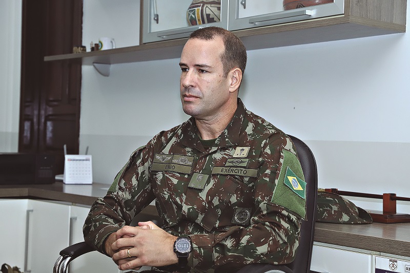 Oficial do Exército Brasileiro em uniforme camuflado, sentado em um escritório.