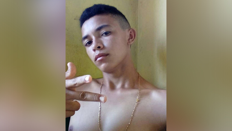 Jovem com corte de cabelo moderno e corrente dourada posando para foto.