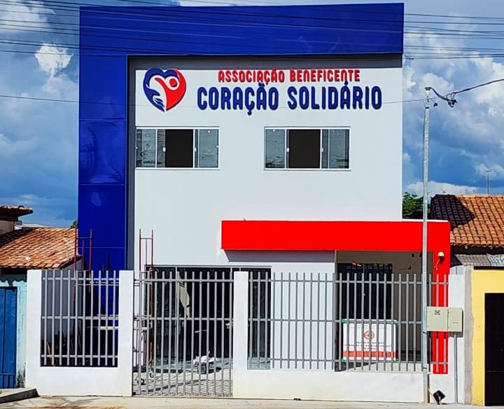 Fachada da Associação Beneficente Coração Solidário com prédio branco e azul.