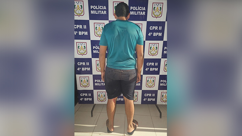 Homem de costas em frente a um painel da Polícia Militar do Pará.