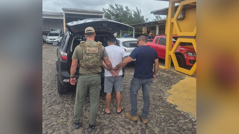 Policiais civis do CORE prendendo um homem com as mãos algemadas ao lado de um SUV preto.