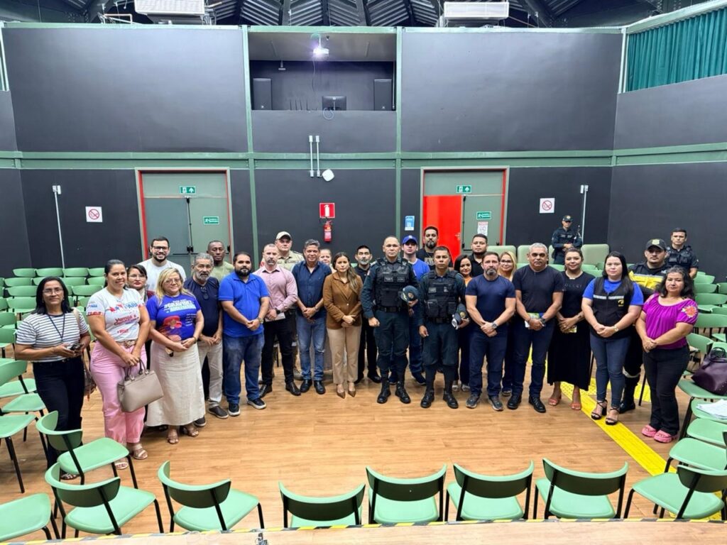 Grupo diverso de pessoas, incluindo seguranças, em auditório ou sala de conferências.