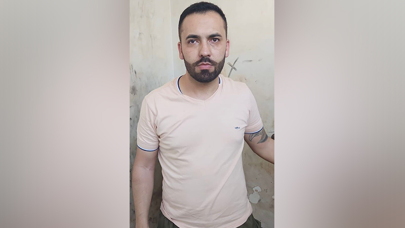 Homem barbudo de camiseta rosa olhando para frente.