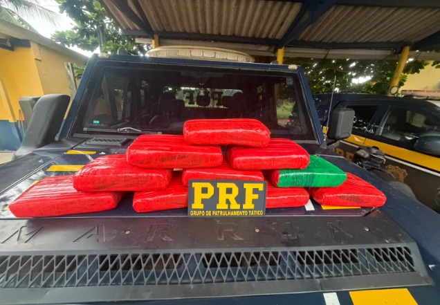 Pacotes de drogas apreendidas sobre o capô de uma viatura da PRF.