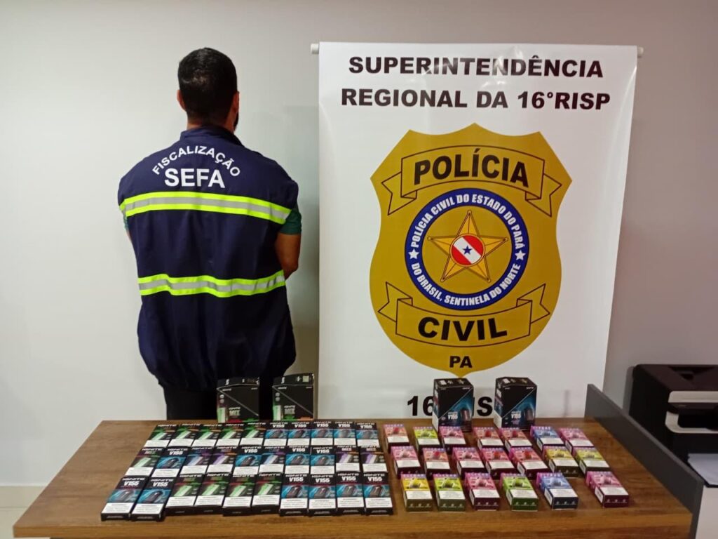 Homem de uniforme SEFA ao lado de mesa com vapes apreendidos e banner da Polícia Civil do Pará.