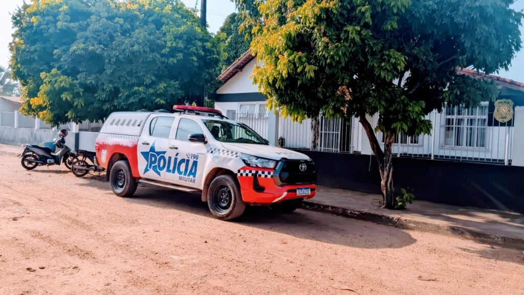 Pick-up Toyota Hilux da Polícia Militar estacionada em rua de terra.