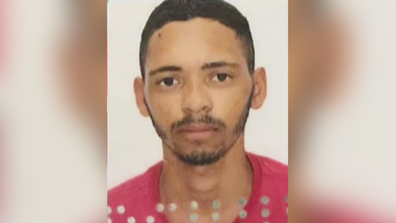 Homem jovem com cabelo curto e barba rala usando camiseta rosa de bolinhas.