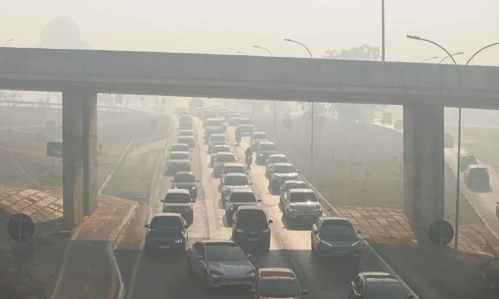 Fila de carros em rodovia movimentada sob neblina ou poluição.