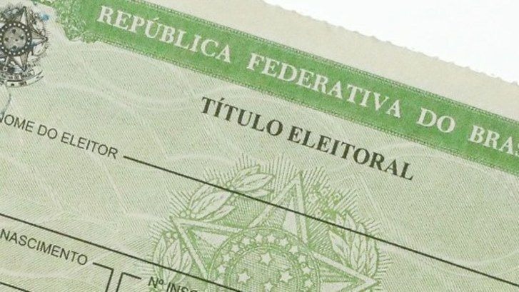Close-up de um Título Eleitoral brasileiro verde, mostrando o Brasão da República e os campos 'Nome do Eleitor' e 'Título Eleitoral'.