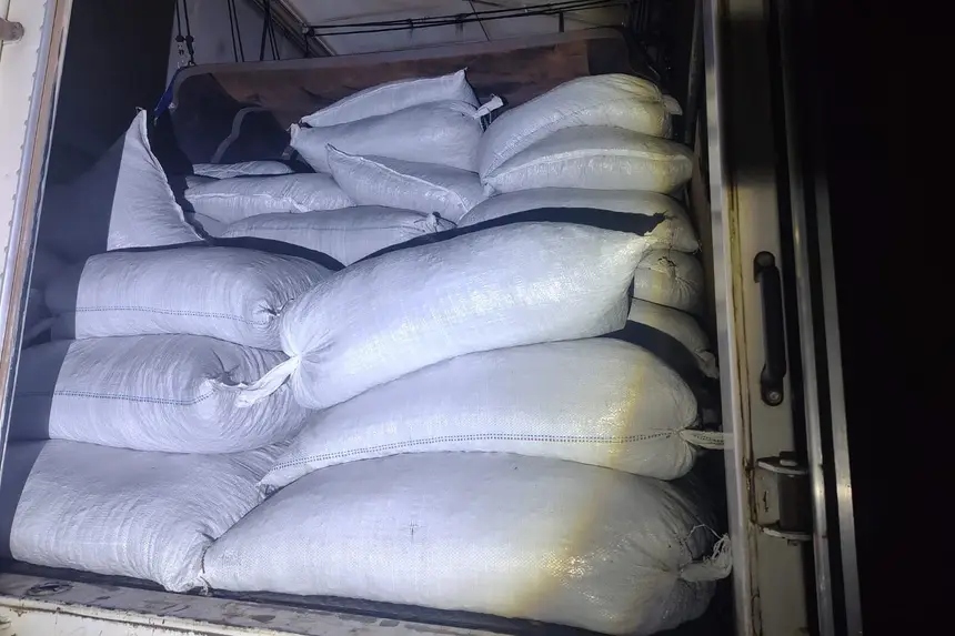 Sacos brancos empilhados no interior de um veículo de carga.