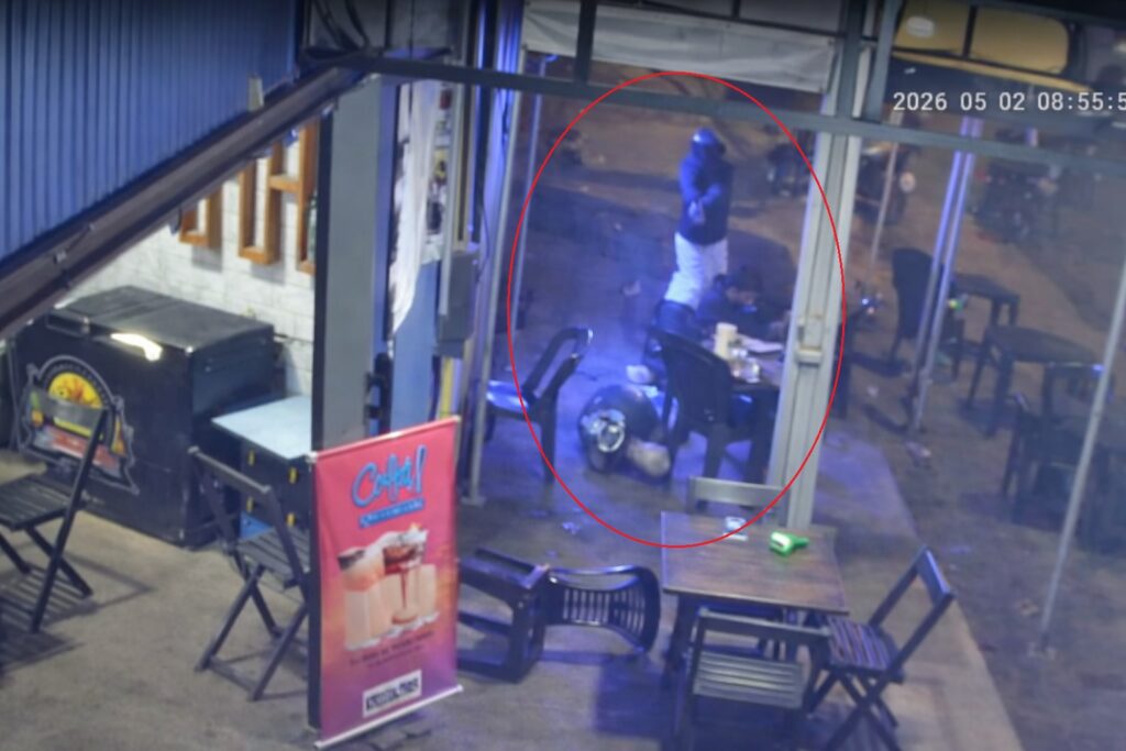 Imagem de segurança noturna mostrando um indivíduo armado em um estabelecimento.