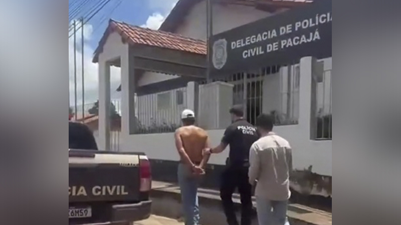 Homem algemado sendo conduzido por policiais em frente à Delegacia de Polícia Civil de Pacajá.