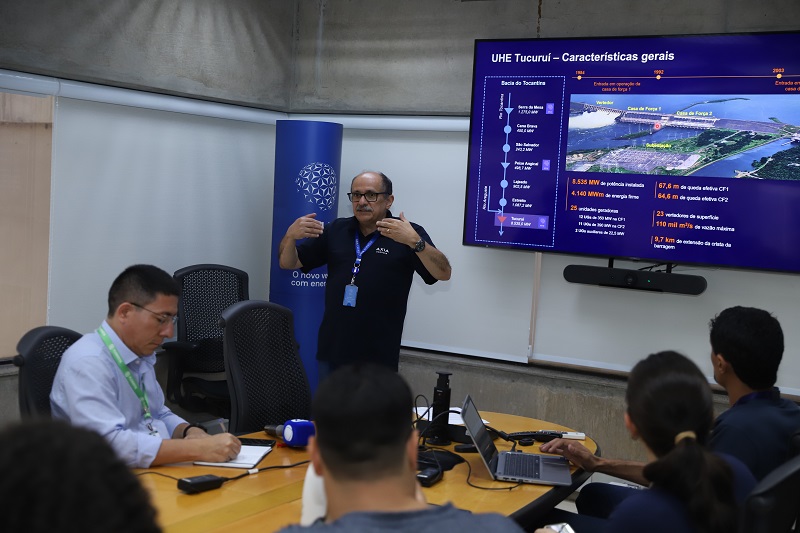 Homem apresentando sobre a UHE Tucuruí em sala de aula com plateia atenta.