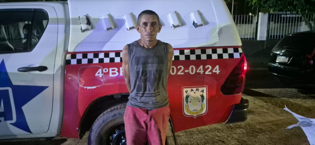 Homem em frente a viatura da Polícia Militar do Pará, com as mãos para trás.