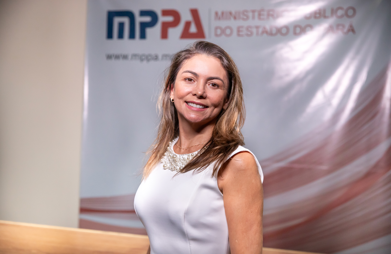 Mulher sorrindo em frente ao banner do Ministério Público do Estado do Pará (MPPA).