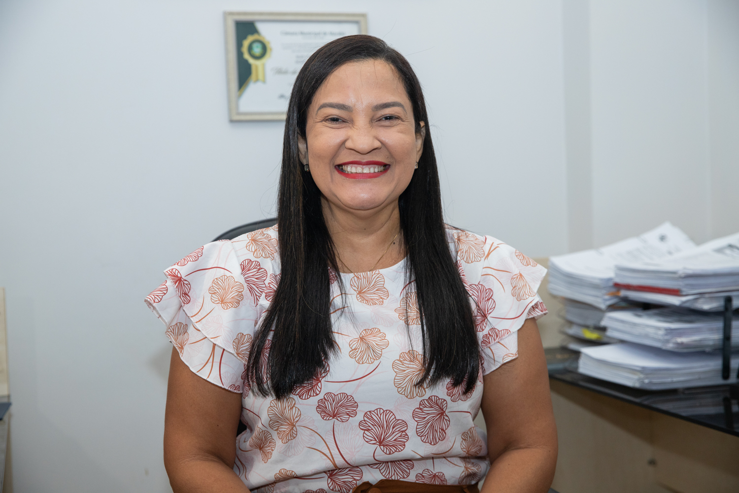 Mulher de meia-idade sorrindo em ambiente de escritório.