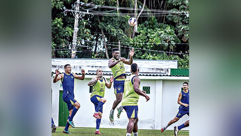 Jogadores de futebol em treino de cabeceio no campo gramado.