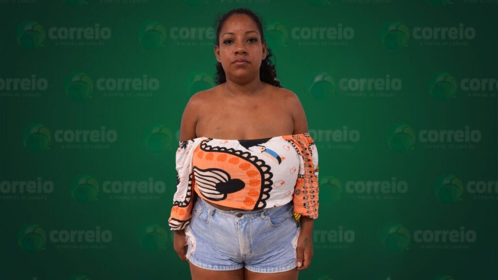 Mulher com blusa ombro a ombro e shorts jeans em frente a fundo verde com logos "correio".