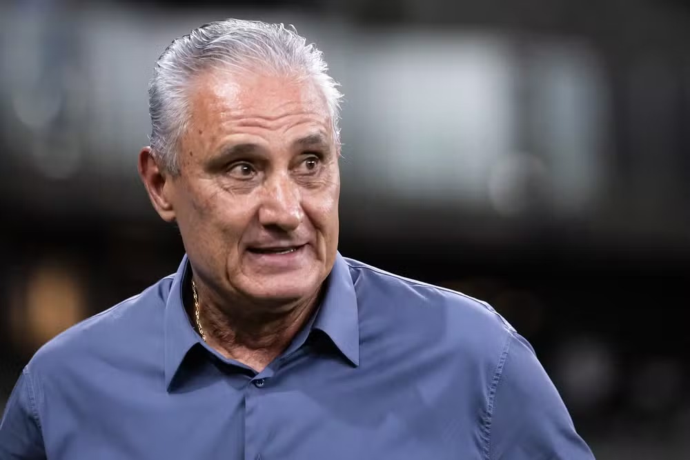Foco no rosto de Tite, treinador de futebol brasileiro, com expressão atenta.