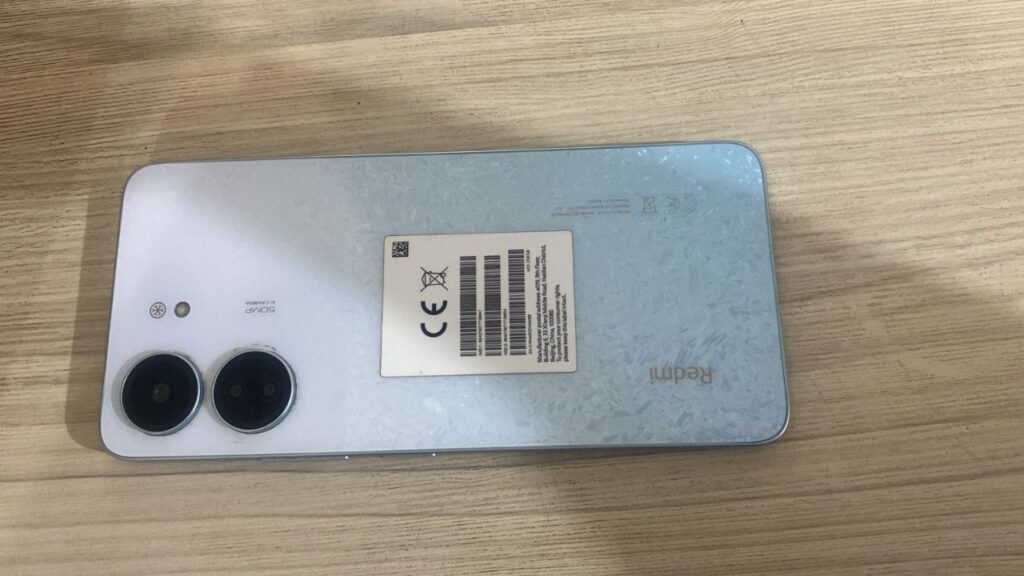 Traseira de smartphone Redmi azul claro com etiqueta de certificação e câmera de 50MP.