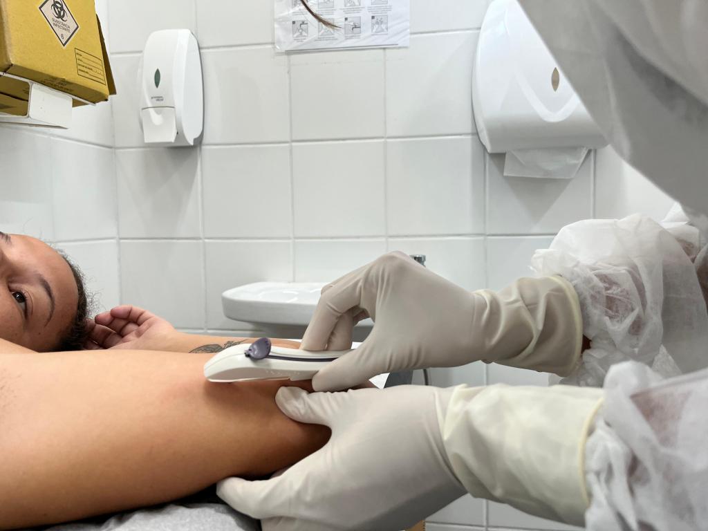 Profissional de saúde inserindo implante contraceptivo no braço de um paciente.