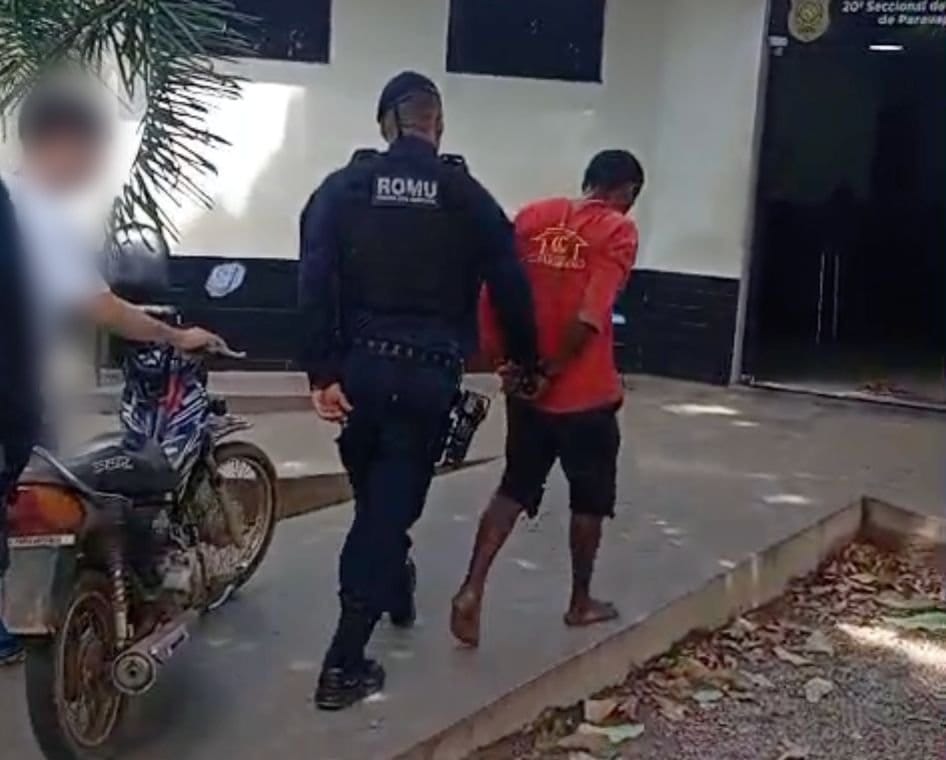 Policial da ROMU escoltando homem algemado, com moto ao lado.