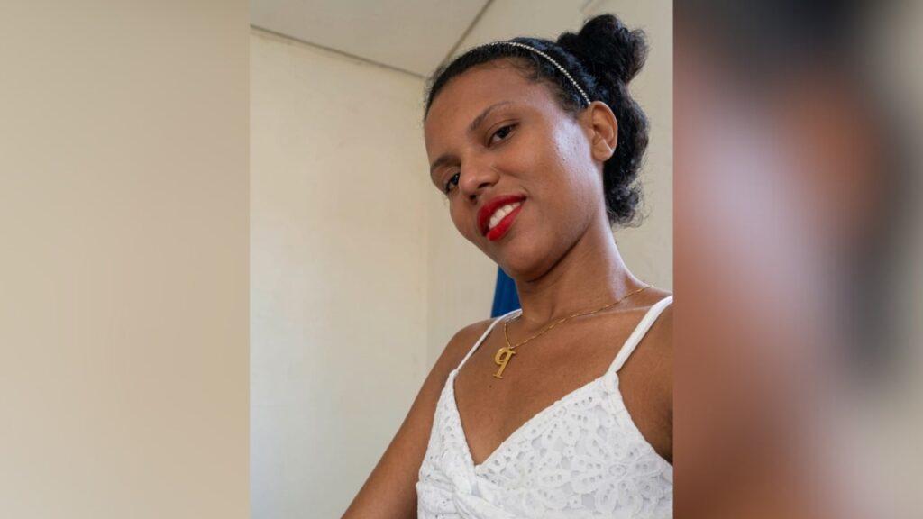 Mulher jovem sorrindo com batom vermelho e top de renda branca.