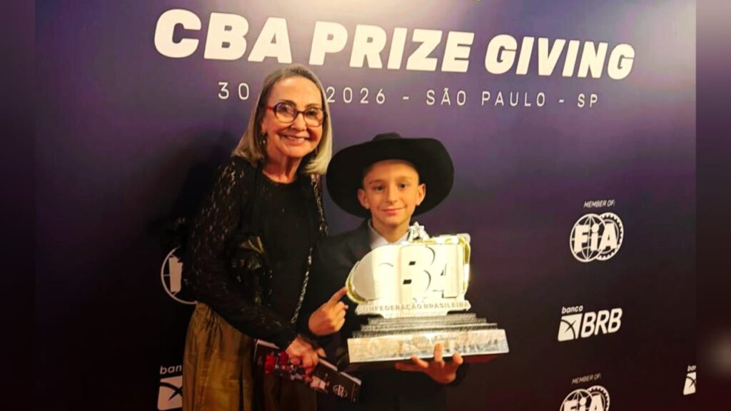 Mulher e menino de chapéu cowboy com troféu da Confederação Brasileira em evento de premiação.