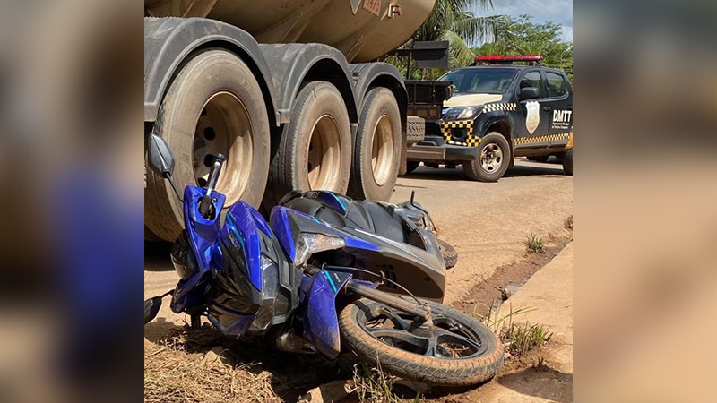 Motocicleta azul caída ao lado de um caminhão em um acidente de trânsito.