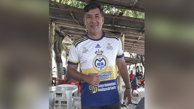 Homem sorrindo e fazendo 'legal' com camisa de time de futebol personalizada.