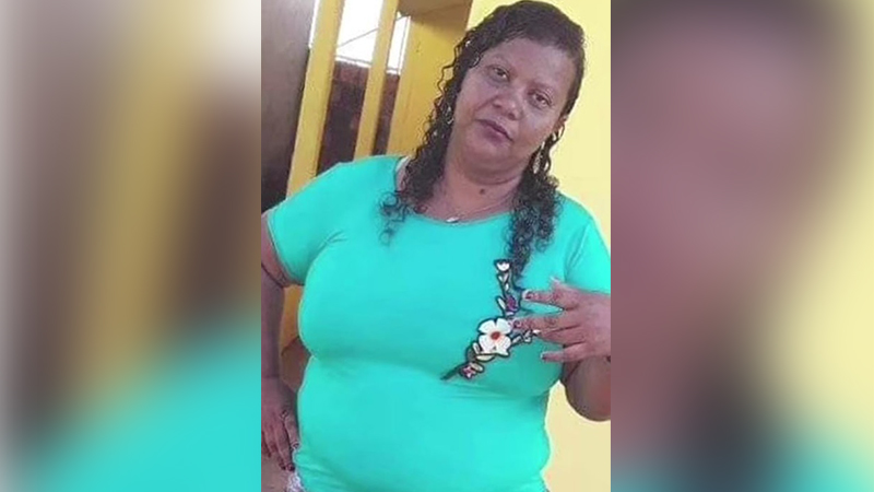 Mulher de meia-idade com cabelo cacheado e camiseta turquesa estampada.