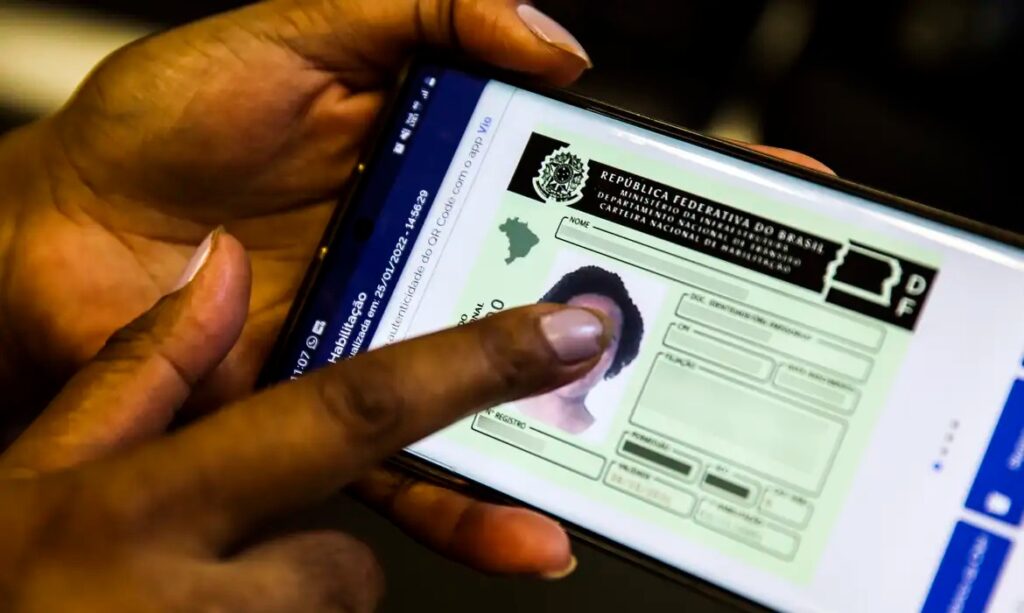 Mão segurando um smartphone com a Carteira Nacional de Habilitação (CNH) digital exibida na tela.