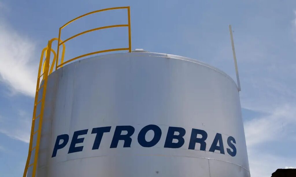Tanque de armazenamento com logo Petrobras e corrimão amarelo sob céu azul.