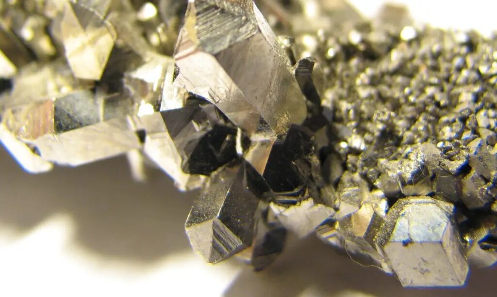 Close-up de um aglomerado de cristais minerais com brilho metálico e formas geométricas angulares.