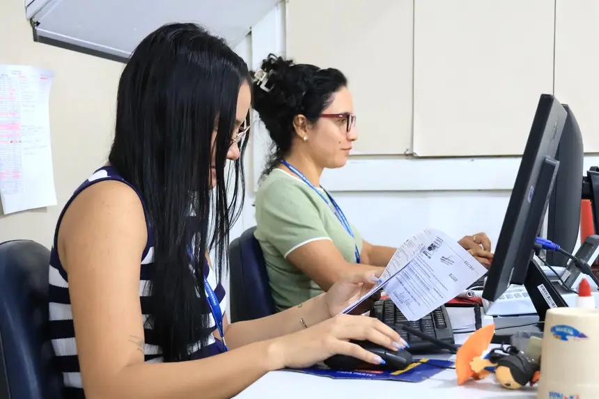Duas mulheres trabalhando em computadores em um escritório.