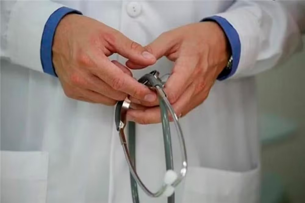 Mãos de médico segurando um estetoscópio.