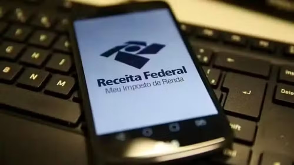 Smartphone com o aplicativo "Receita Federal Meu Imposto de Renda" na tela, sobre um teclado.
