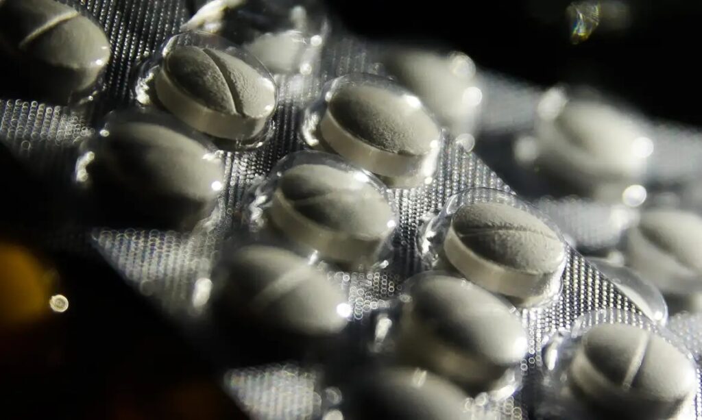 Foco em cartela de comprimidos brancos e ovais.