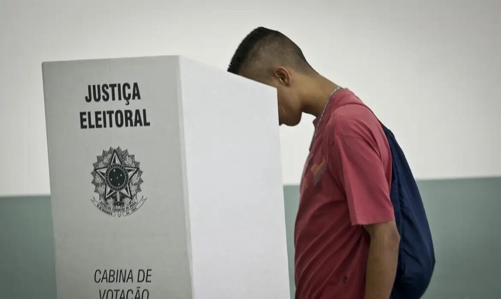 Jovem votando em cabine eleitoral da Justiça Eleitoral no Brasil.