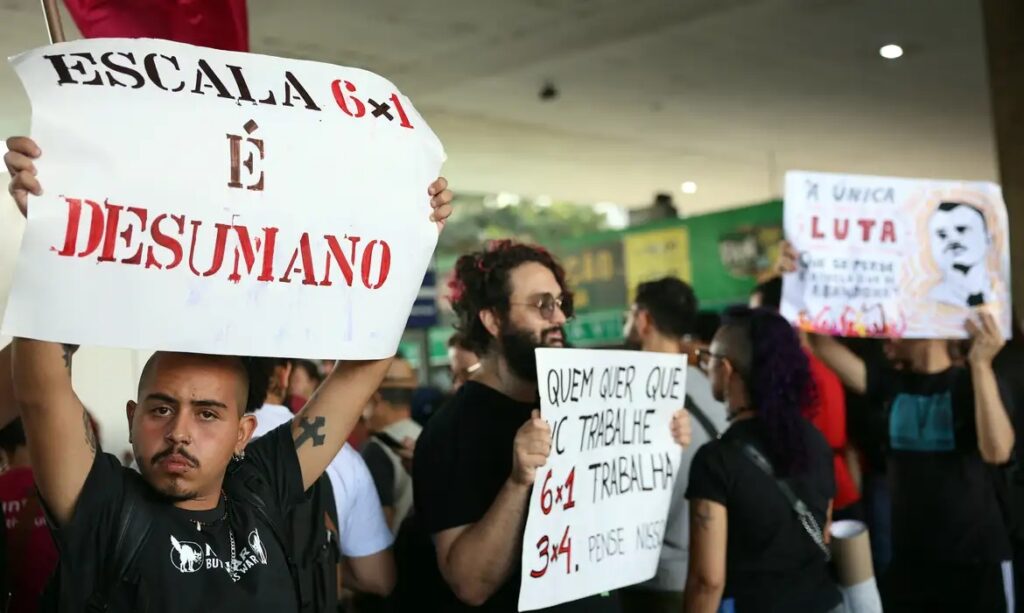 Manifestantes segurando cartazes contra a escala de trabalho 6x1 em um protesto.