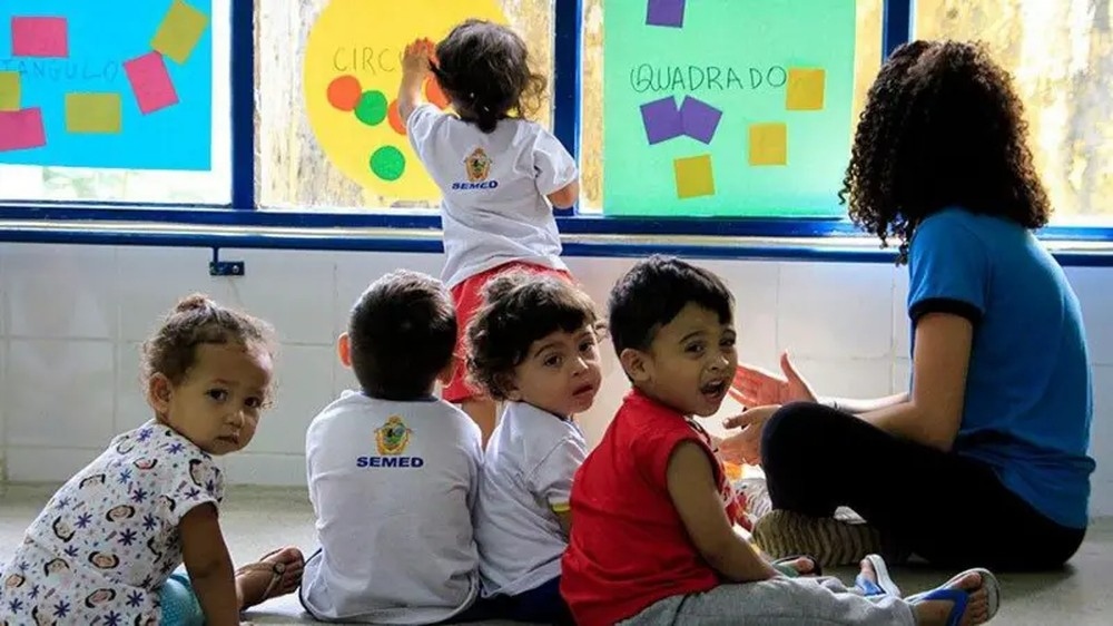 Crianças da educação infantil aprendendo formas geométricas em sala de aula.