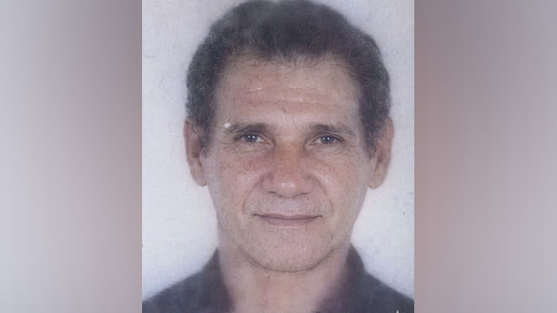 Homem de meia-idade com cabelo escuro e rugas faciais, olhando para a câmera.