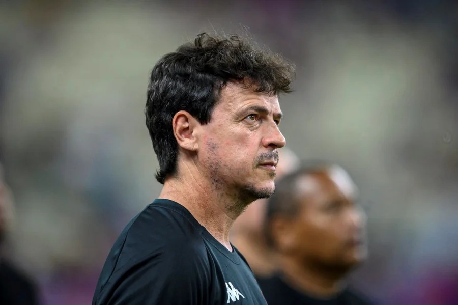 Homem de cabelo escuro e camisa preta olhando para o lado esquerdo com expressão séria.