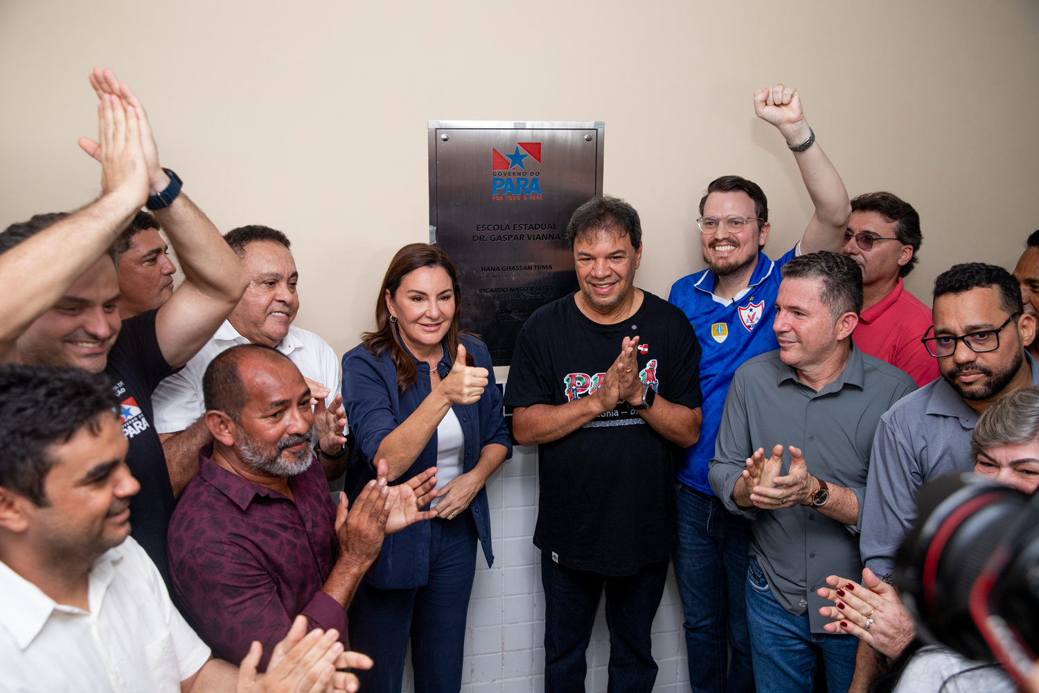 Grupo de pessoas sorrindo e aplaudindo em frente a uma placa de inauguração da Escola Estadual Dr. Gaspar Vianna pelo Governo do Pará.