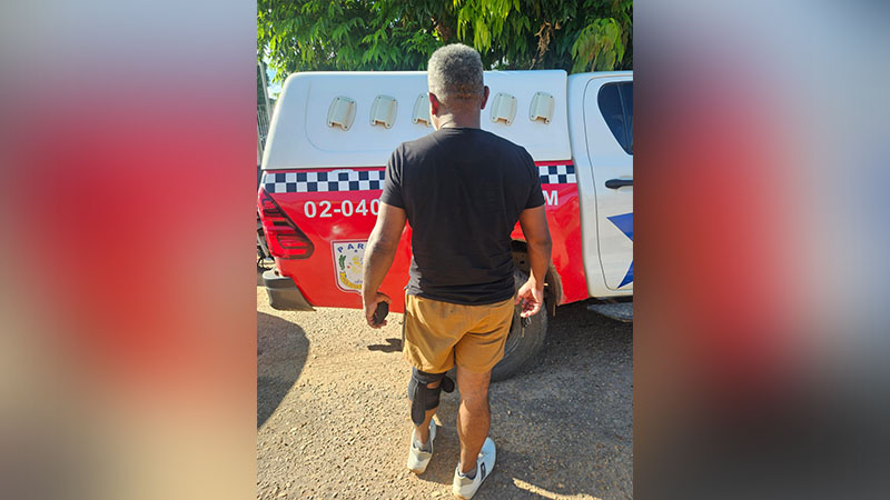 Homem de costas com órtese na perna, caminhando perto de viatura.