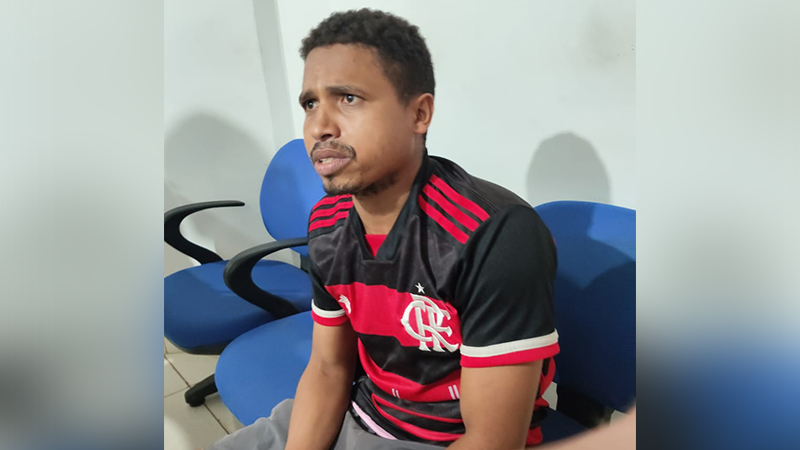 Homem em camisa do Flamengo, sentado, com expressão séria.