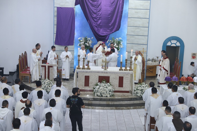 Cerimônia religiosa católica em igreja com vários padres e um bispo no altar.